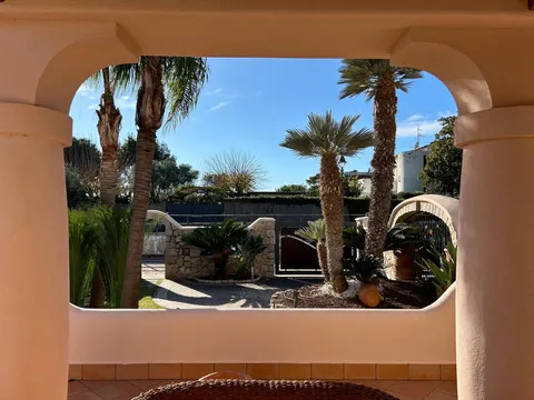 Una terrazza ad archi che guarda sulle palme del giardino