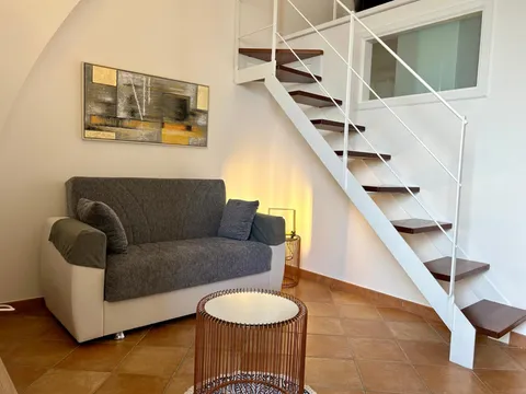 Zona giorno con divano e scala per il soppalco