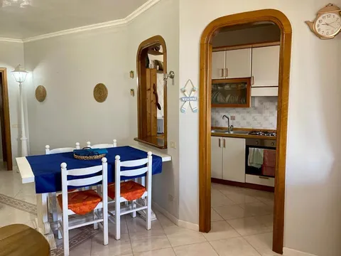 Zona pranzo con tovaglia blu e la cucina dietro