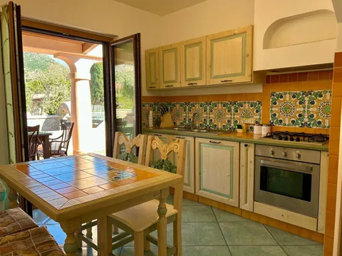 Cucina con tavolo in maiolica e porta sulla terrazza