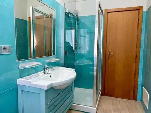 Bagno con doccia e piastrelle turchesi