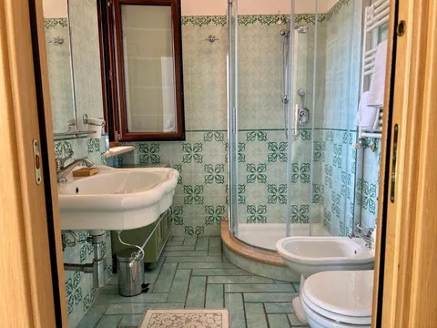 Bagno con doccia angolare e piastrelle decorate