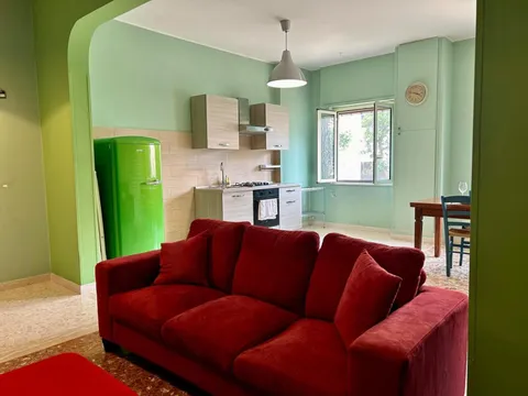 Soggiorno con divano rosso e frigorifero verde
