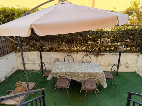 Giardino con tavolo e sedie sotto un grande ombrellone